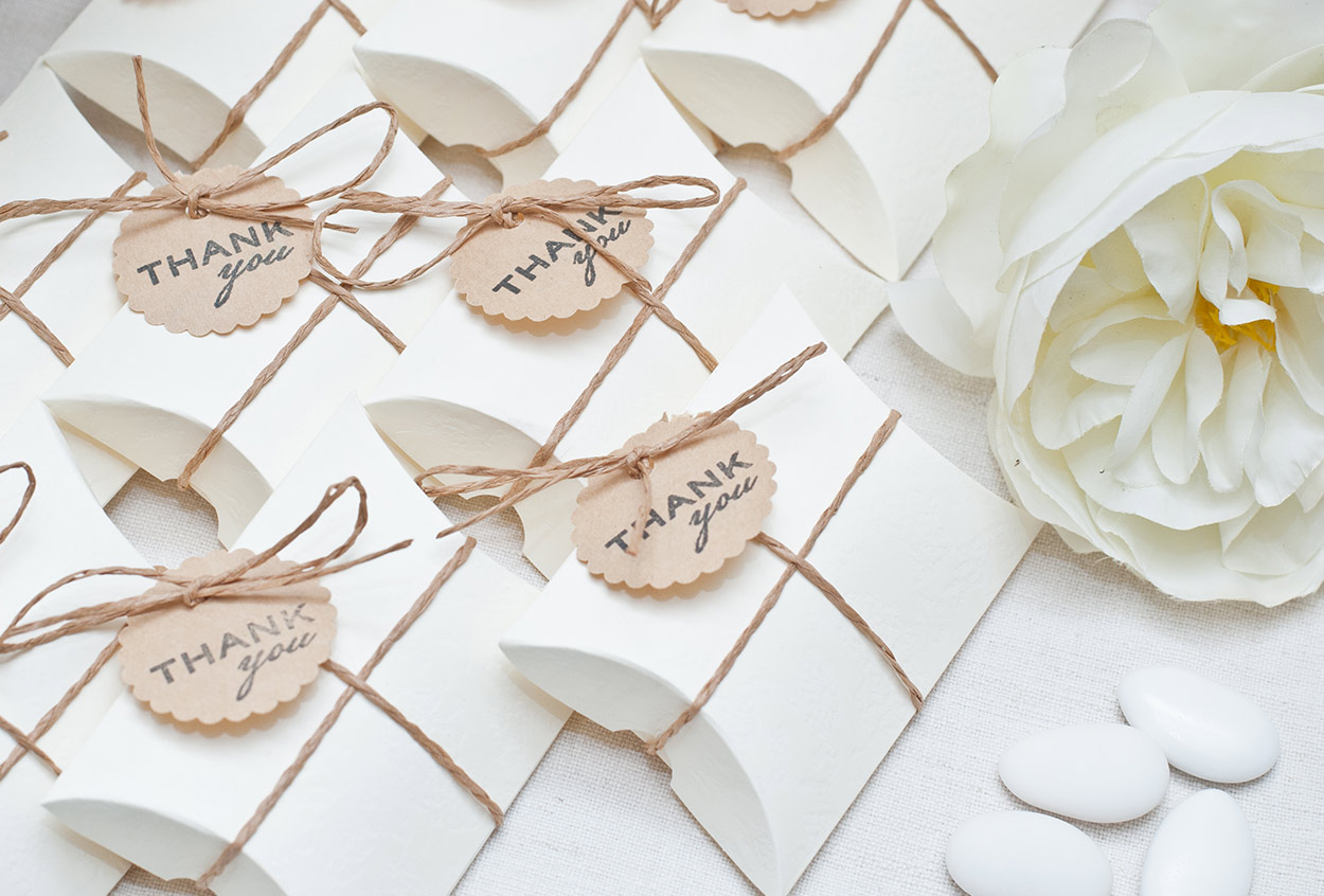 Wedding favor gift boxes laid out on a white table.