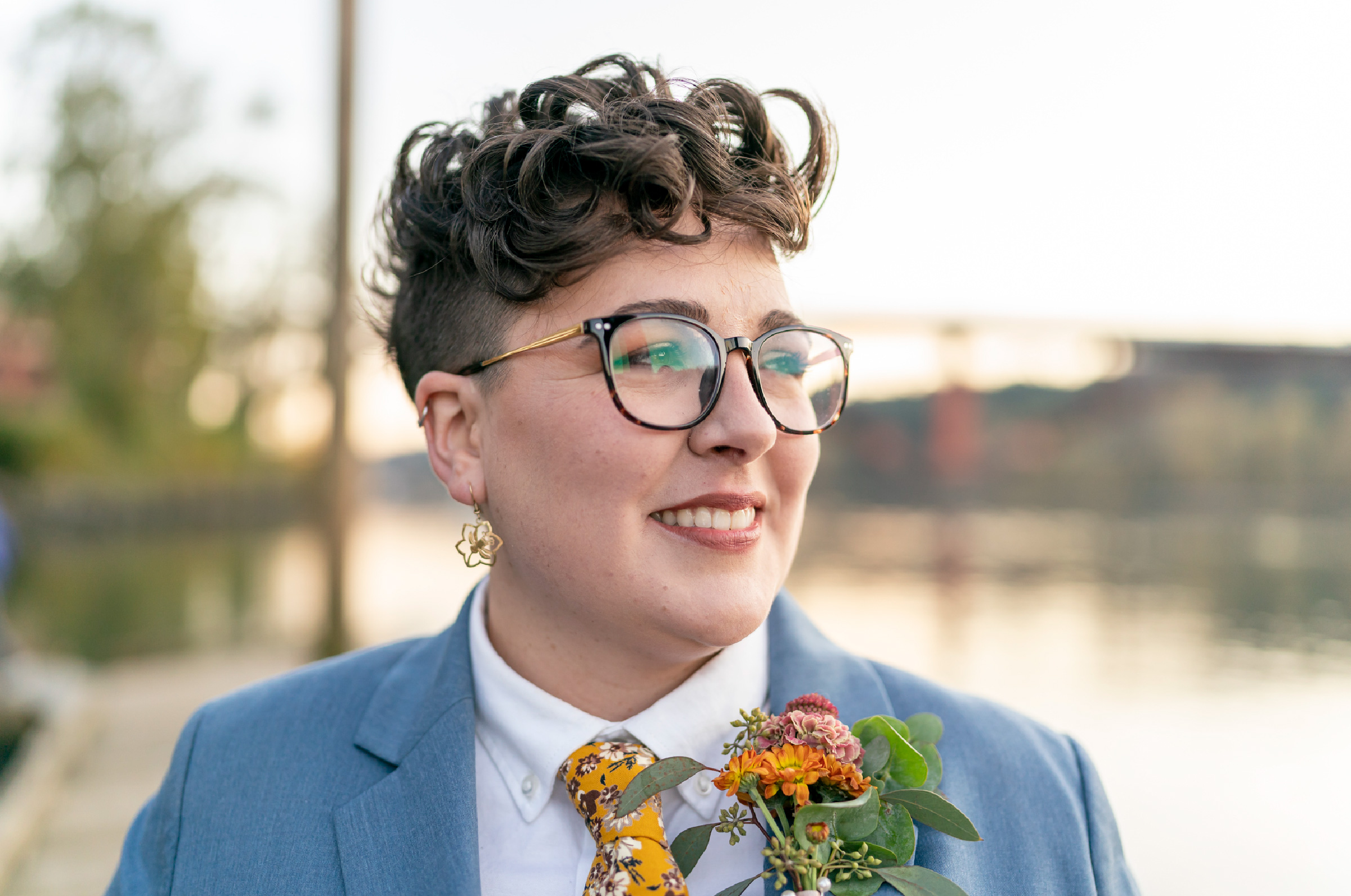 A woman wearing androgynous wedding attire during the sunset. 