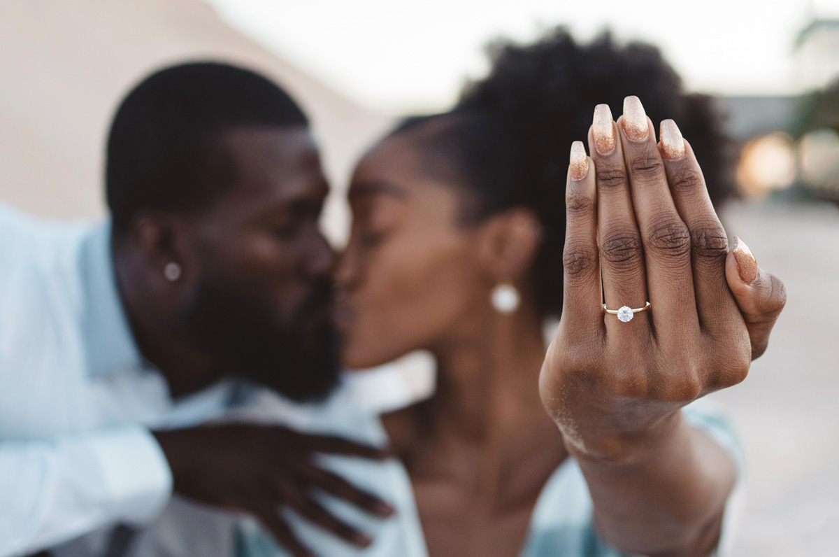 couple kissing showing off engagement ring.