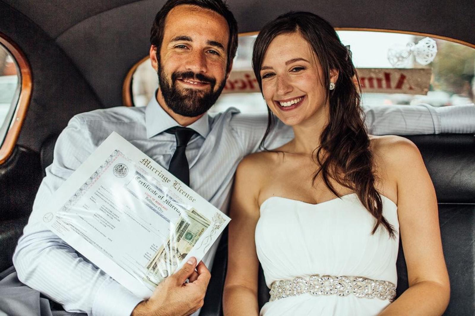 bride and groom sitting in the backseat of car posing with marriage license