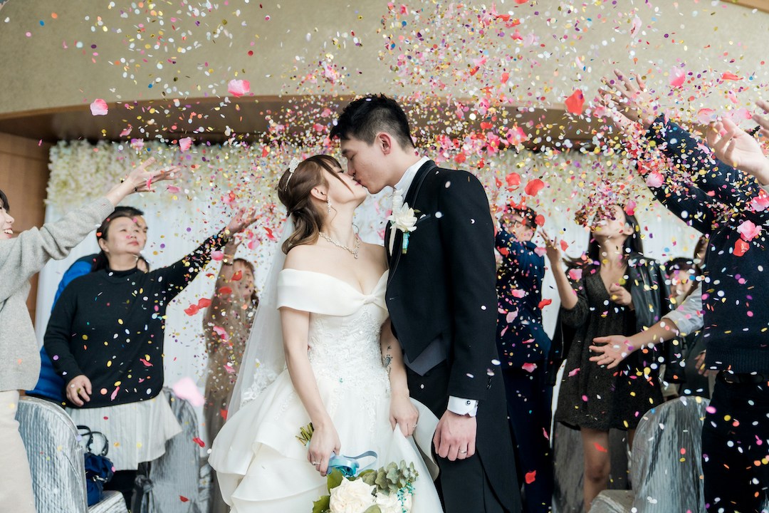 Guests gifting young ethnic newlyweds during wedding celebration with confetti