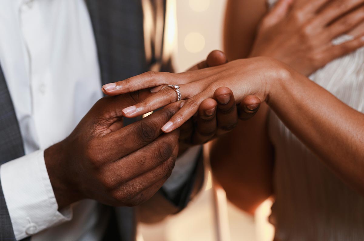 Close up of man putting wedding ring on woman's finger