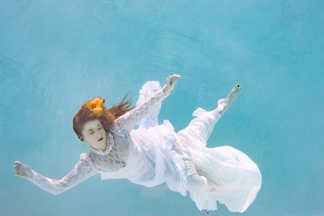 Woman in white floating underwater