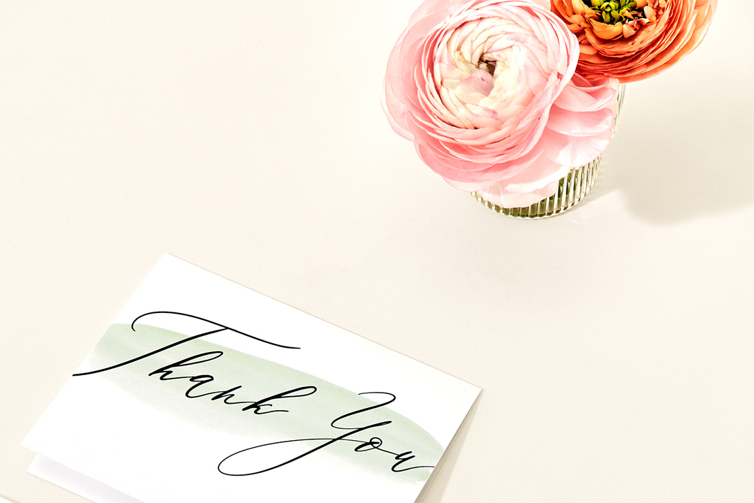 wedding thank you notes on a marble counter next to a ring dish and a vase of pink peonies