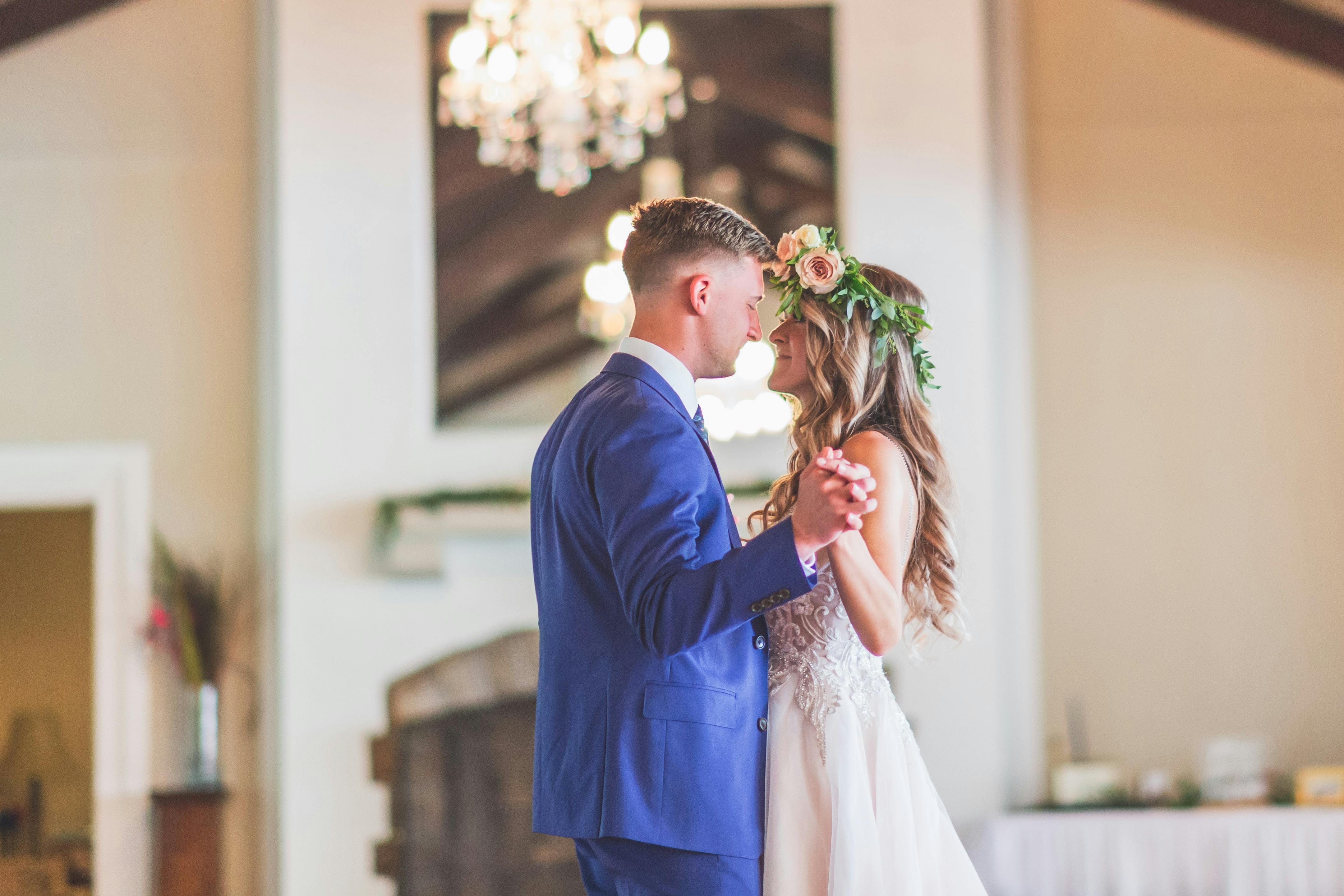 Newlyweds dancing inside of their wedding reception venue with bride wearing flower crown