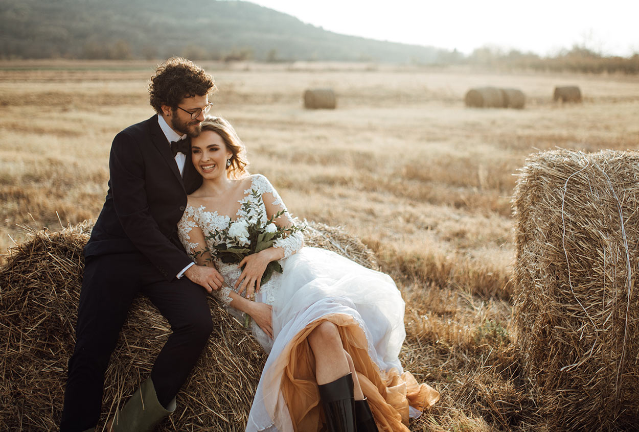 bride and groom sitting on a hay bale