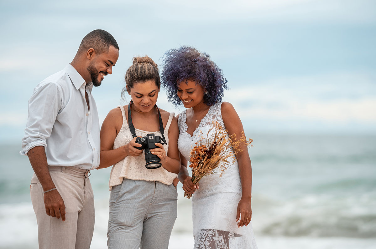 A wedding photographer shows a couple a photo she captured of them during their photoshoot. 