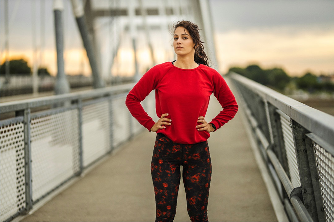 Une coureuse en t-shirt rouge debout sur un pont