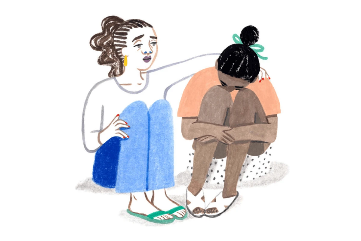 A Monarch by SimplePractice illustration of a woman with a white shirt, blue pants, and green sandals sitting down with her arm around another woman in an orange shirt, polka-dot shorts, and white sandals who is resting her head on her knees and hugging her knees to her chest. 