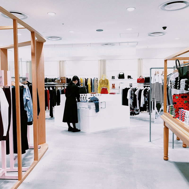 Female worker standing in retail shop that sells women's clothing.