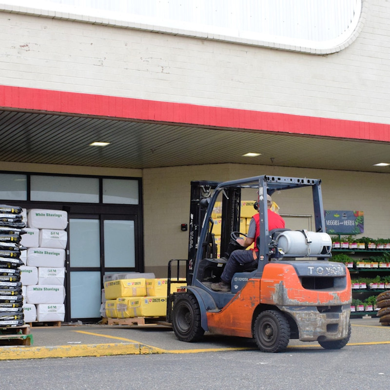 Worker driving forklift at warehouse