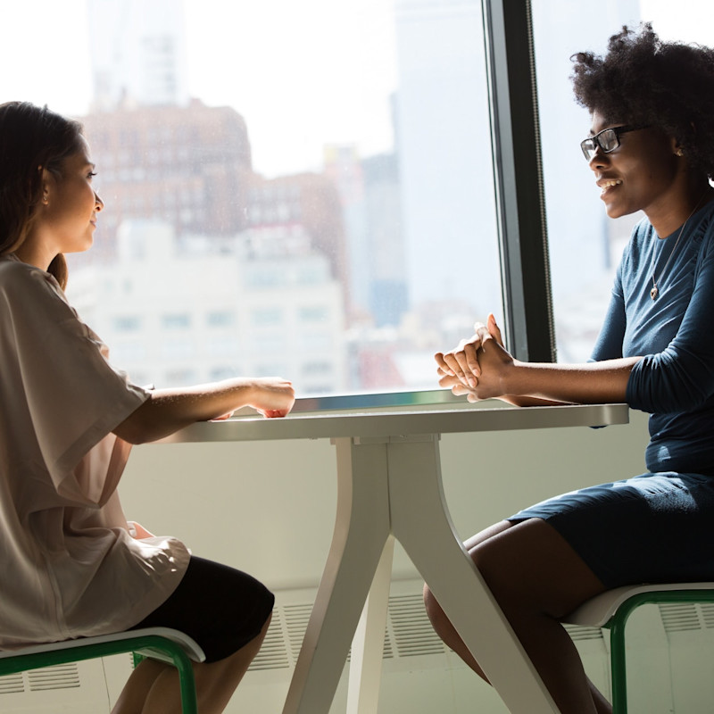 Image: Two women speaking in an office.