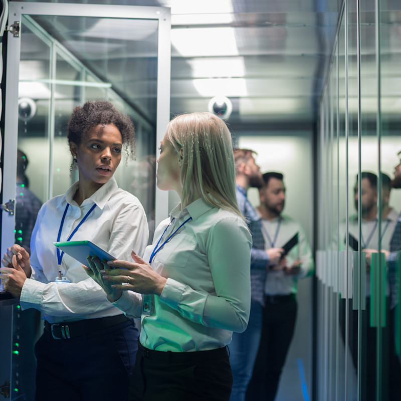 Two women standing in a data centre or communications room