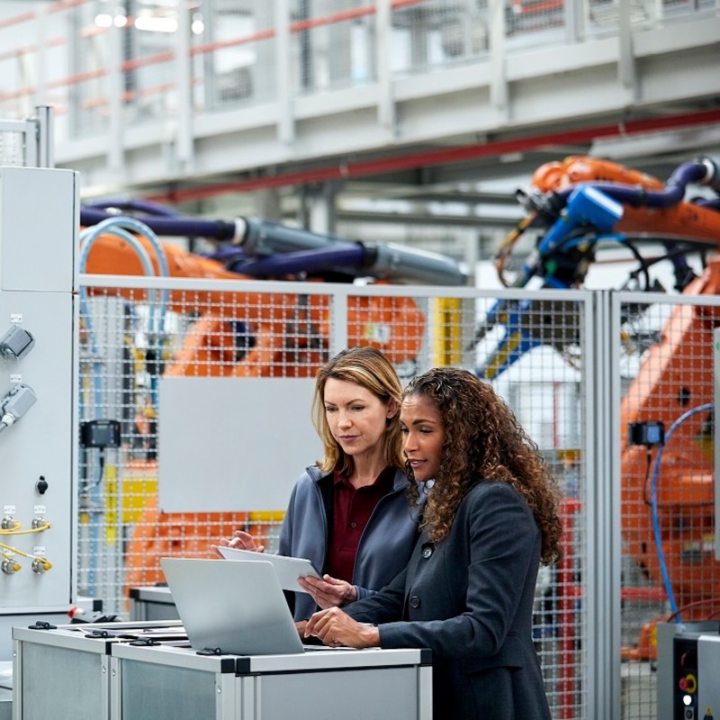 Two colleagues in a factory reviewing a computer screen.