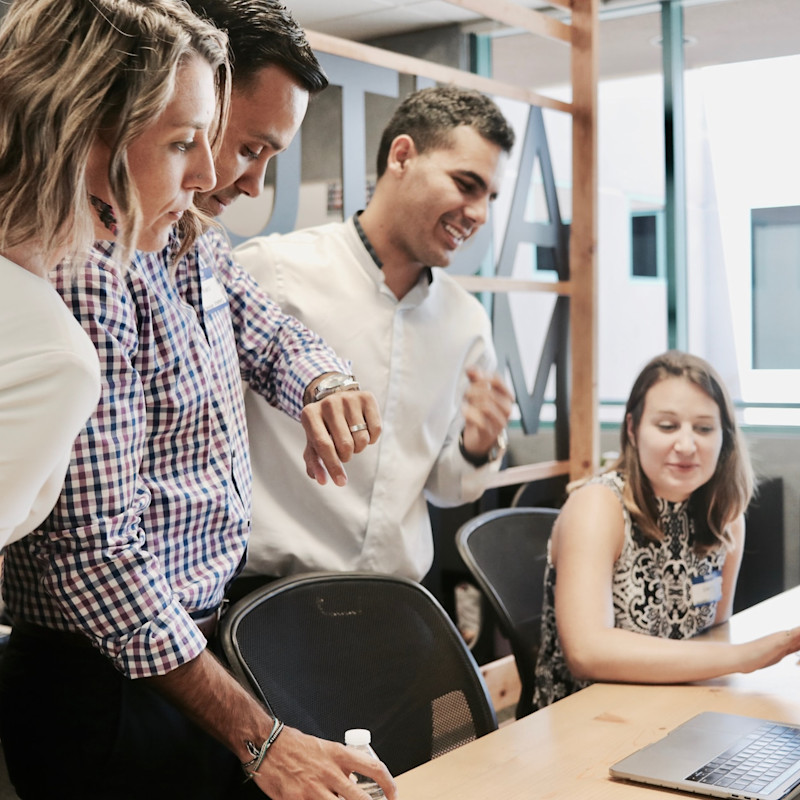 Team of colleagues standing over a desk having a lively conversation.