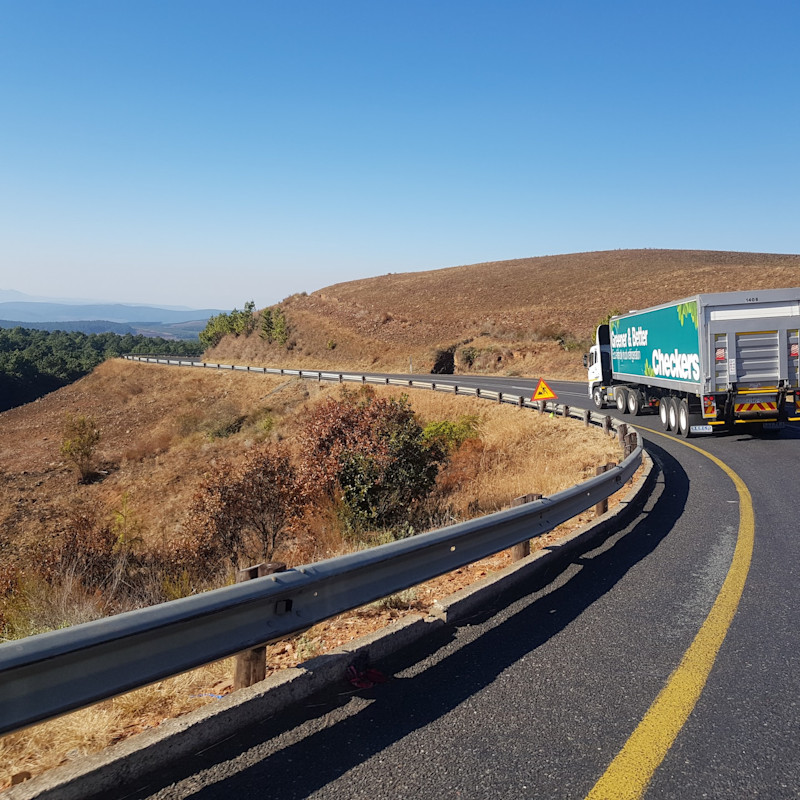 Freighter truck driving on windy country road.