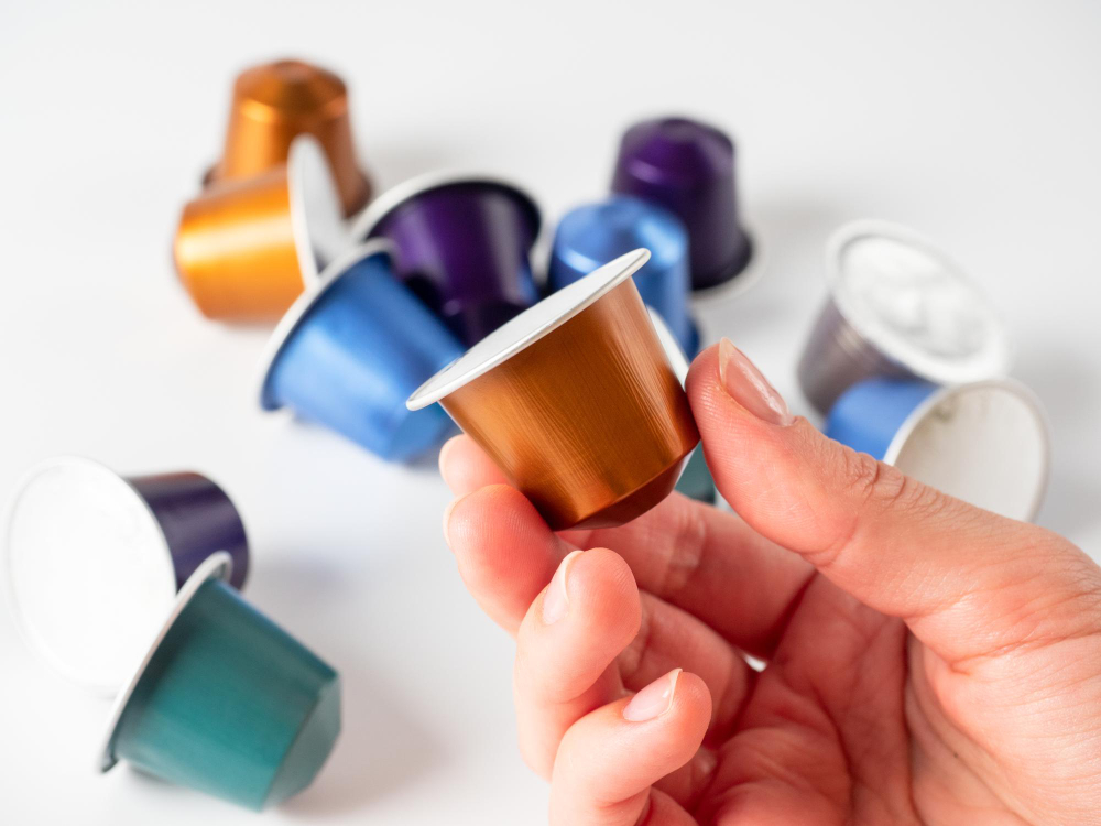 colored-aluminum-capsule-with-ground-coffee-hand-white-background-with-other-capsules-lying-it-modern-methods-making-coffee-capsule-coffee-machine1