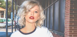 frisuren-fuer-feines-haar Junge Frau mit platinblonden feinen Haaren und stylischer Long Bob Frisur schlendert durch die Straße