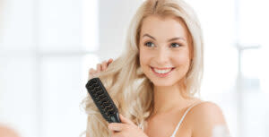 Junge Frau mit blonden langen Haaren kämmt ihre Haare Junge Frau mit blonden langen Haaren kämmt ihre Haare