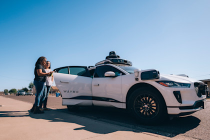 Juana and Minerva opening the door to a Waymo One autonomous ride-hailing vehicle