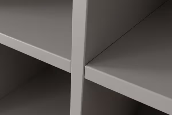 Minimalistische close-up van witte houten planken in een open kast of boekenkast met strakke lijnen en schaduwen.