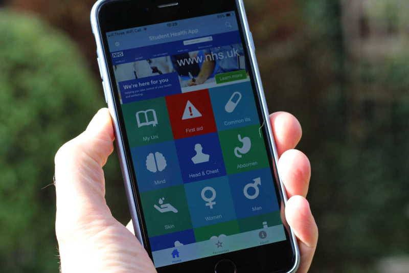 An image of a hand holding an iPhone with the Student Health App open on the screen. 