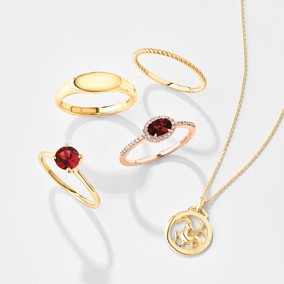 Flatlay of gold rings, some with ruby and garnet gemstones, and a zodiac pendant