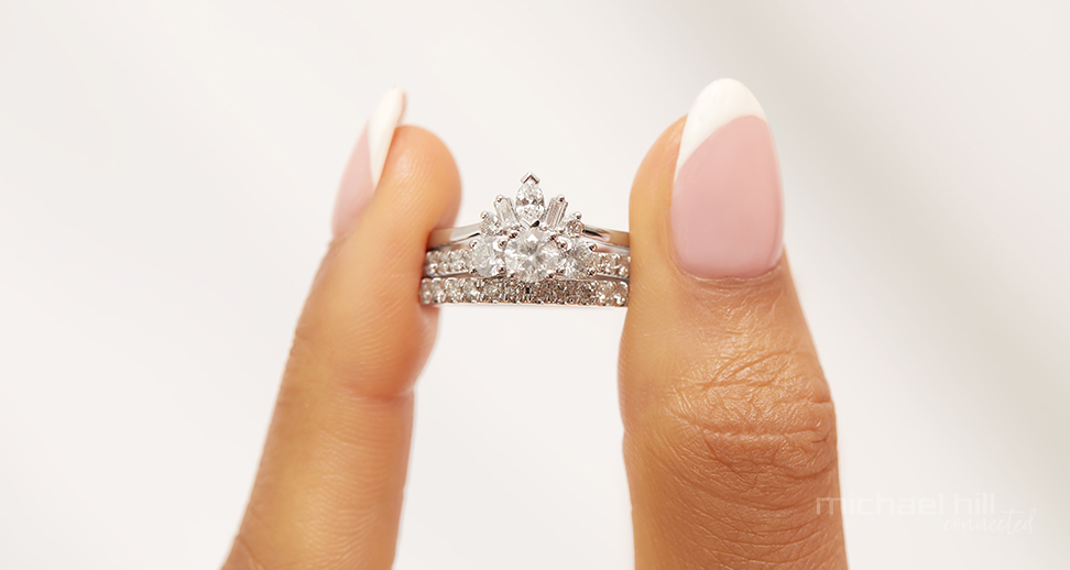 Holding a bridal set featuring a three stone engagement ring