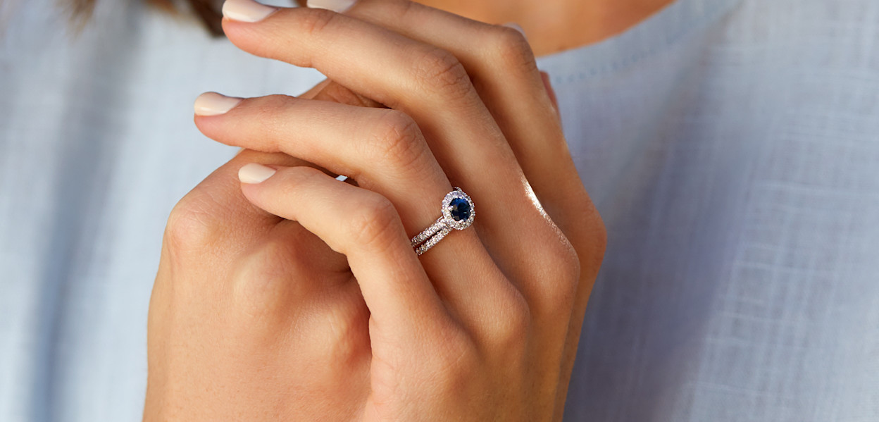 Close up of female hands with a sapphire and white gold bridal set.