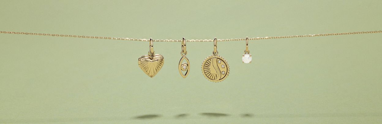 Flatlay of four mixed pendants hanging from a slide on chain