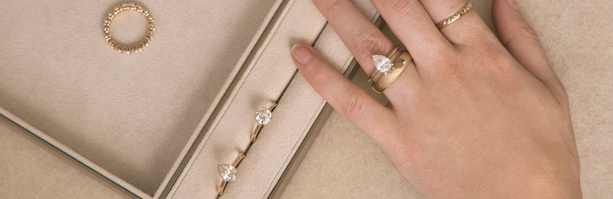 Close up of different engagement rings alongside a model's hand wearing an engagement ring and wedding band