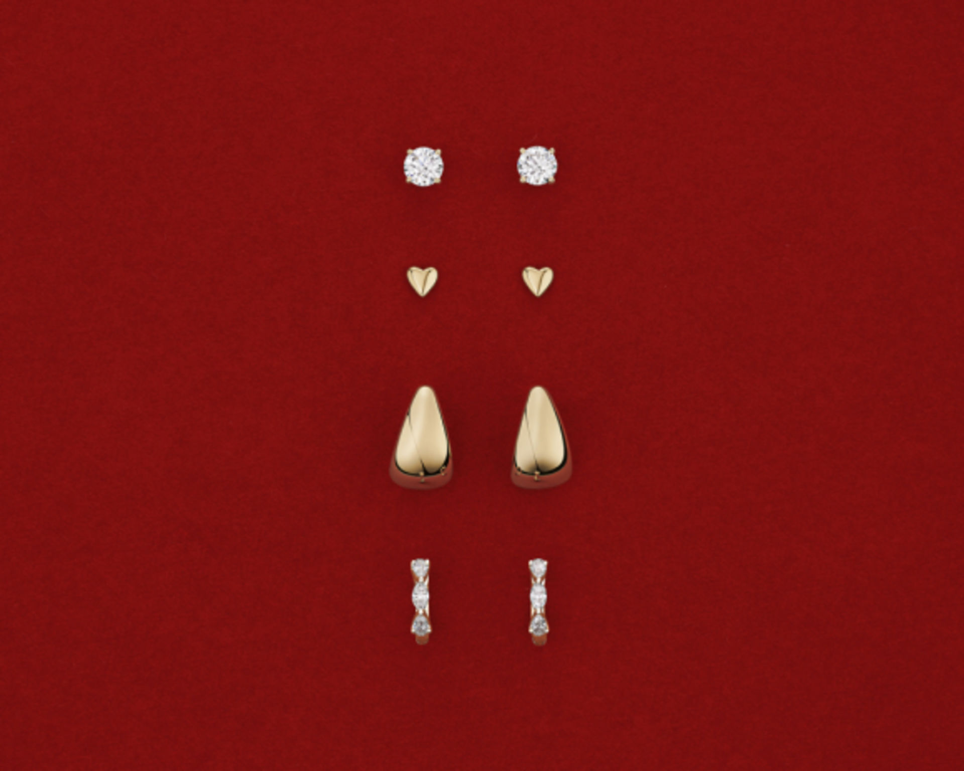 gold and diamond earrings on red background