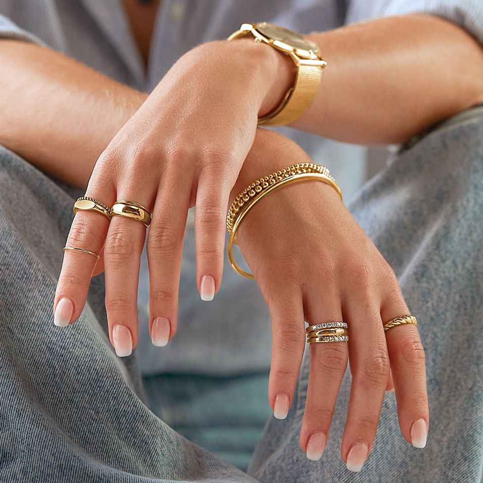 Woman wearing gold ring stacks, bracelets and a gold watch