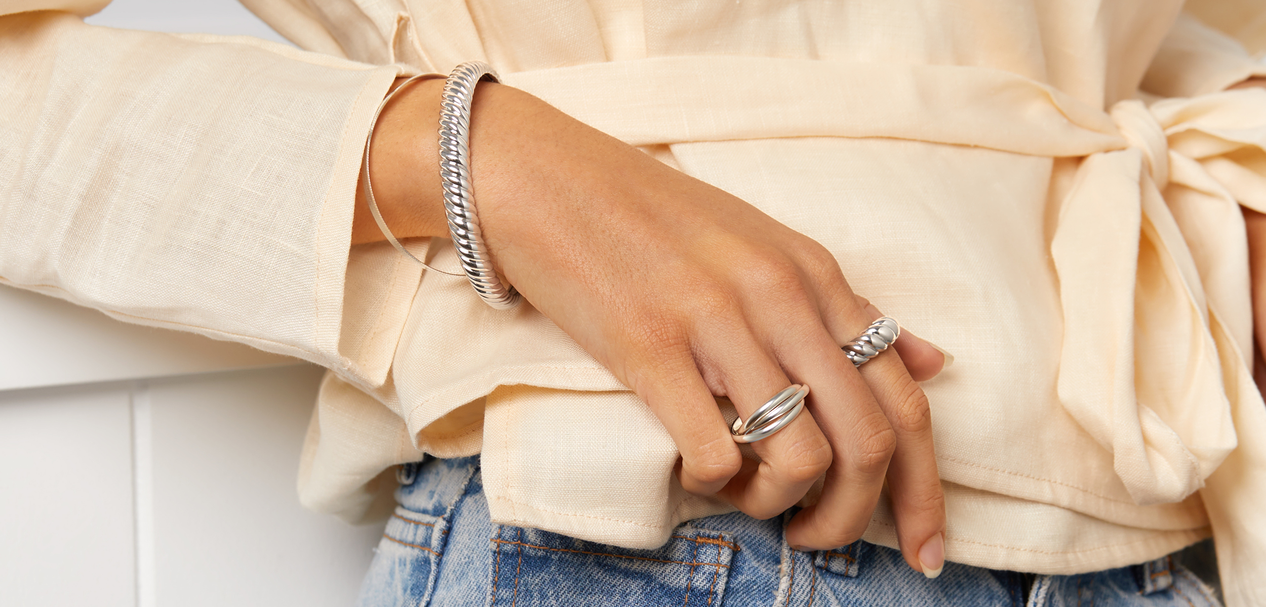 female hand wearing two 925 sterling silver rings and two bangles