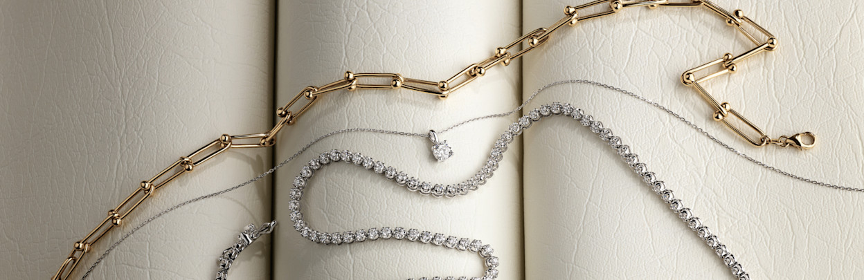 Flat lay of gold chain, diamond pendant and tennis necklace