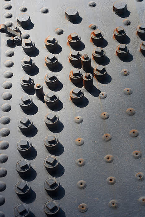 Photograph of the mass of bolts on the side of a steam train boiler.