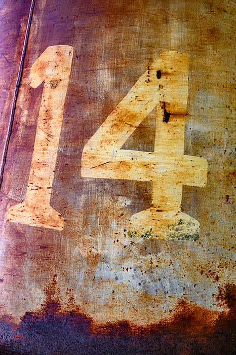 Photograph of the number 14 on a rusty panel.