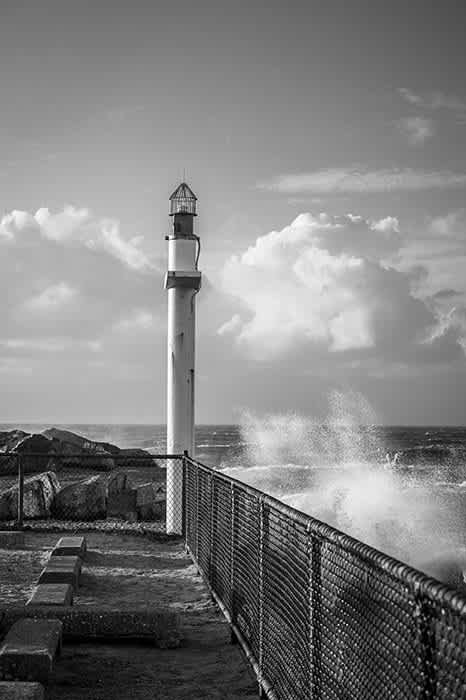Photograph of navigation light at the end of jetty during wild seas.