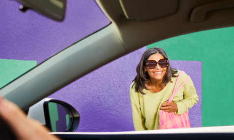 woman in sunglasses with purse smiling from outside passenger window
