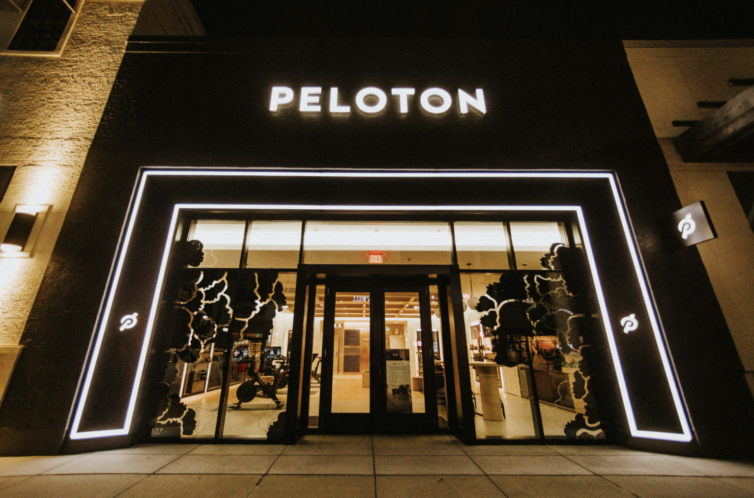 A Peloton showroom front displays artwork, illuminated by lights at night, from a Black artist in celebration of Black History Month.