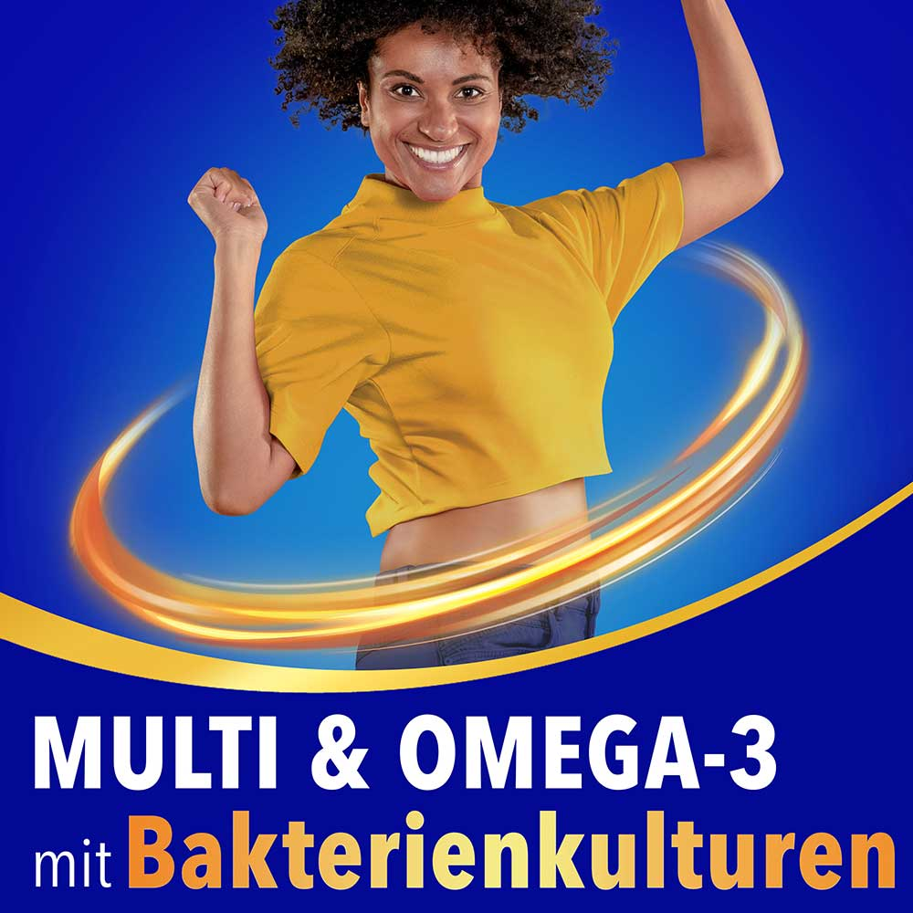 Lächelnde Frau im gelben Shirt springt energiegeladen vor blauem Hintergrund mit dem Text „Multi & Omega-3 mit bakterienkulturen“