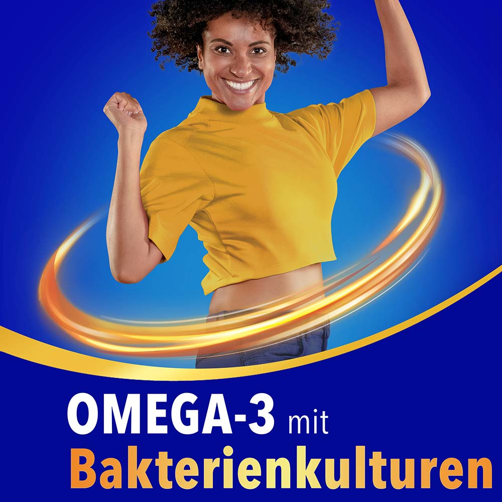 Lächelnde Frau im gelben Shirt springt energiegeladen vor blauem Hintergrund mit dem Schriftzug „Omega-3 mit Bakterienkulturen"