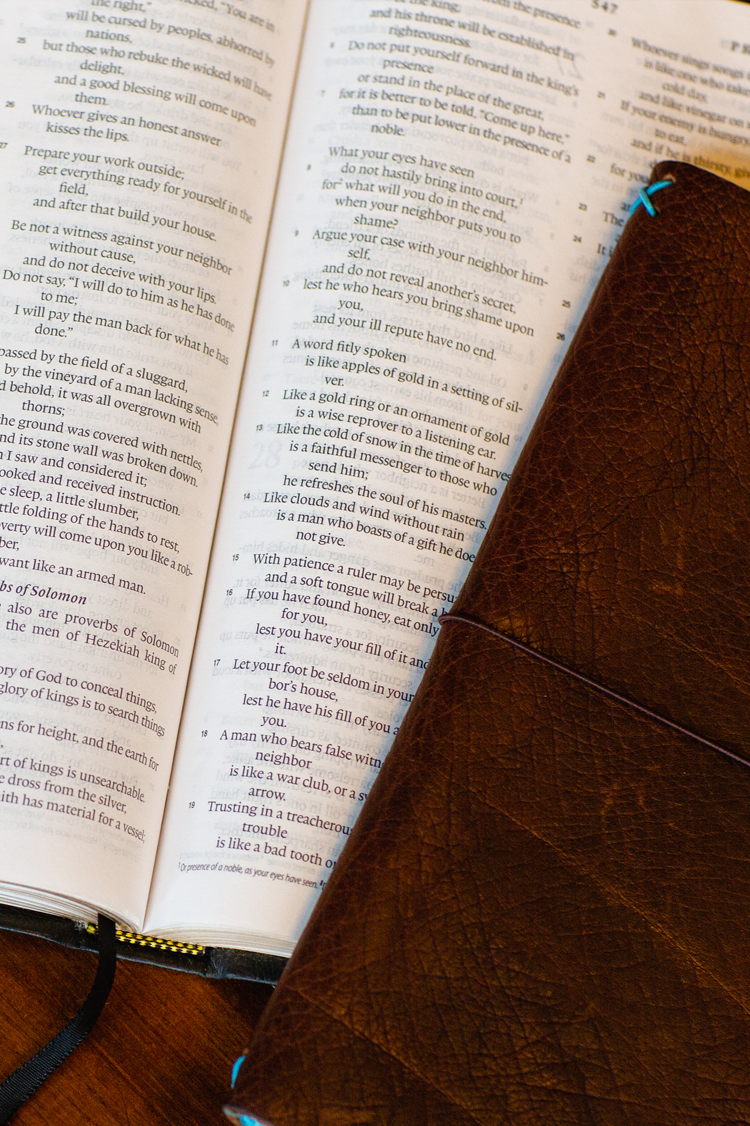 Open Bible displaying Proverbs with a leather journal on a wooden table symbolizing biblical wisdom, truth, and the foundation of faith for Watermark Resources’ Statement of Faith.