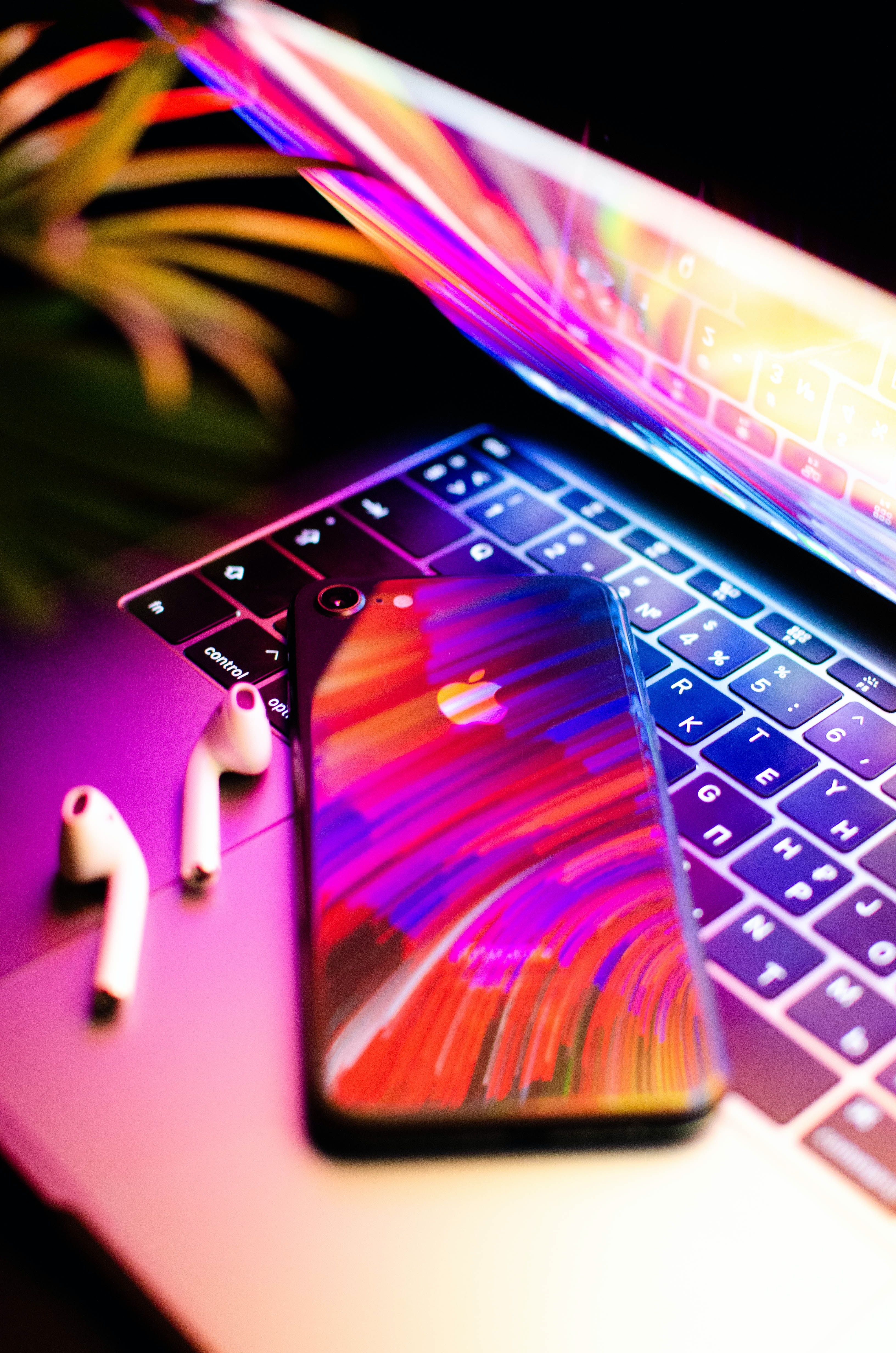 iPhone, AirPods, and Apple computer with rainbow reflection
