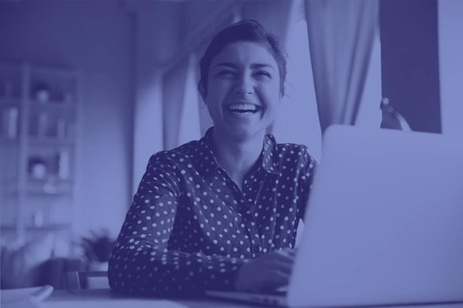 A woman sitting at a laptop laughing