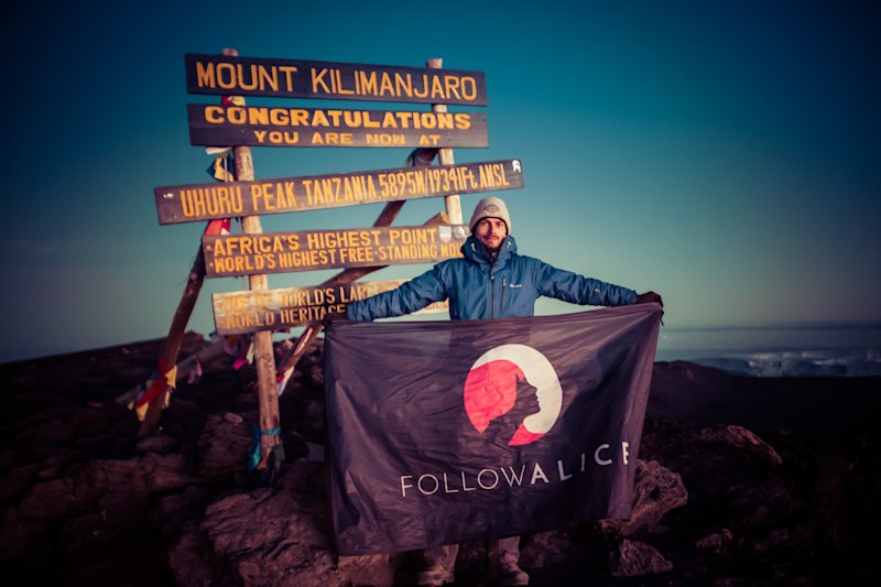 Ambassador Dan flying the Follow Alice flag at the summit of Mount Kilimanjaro