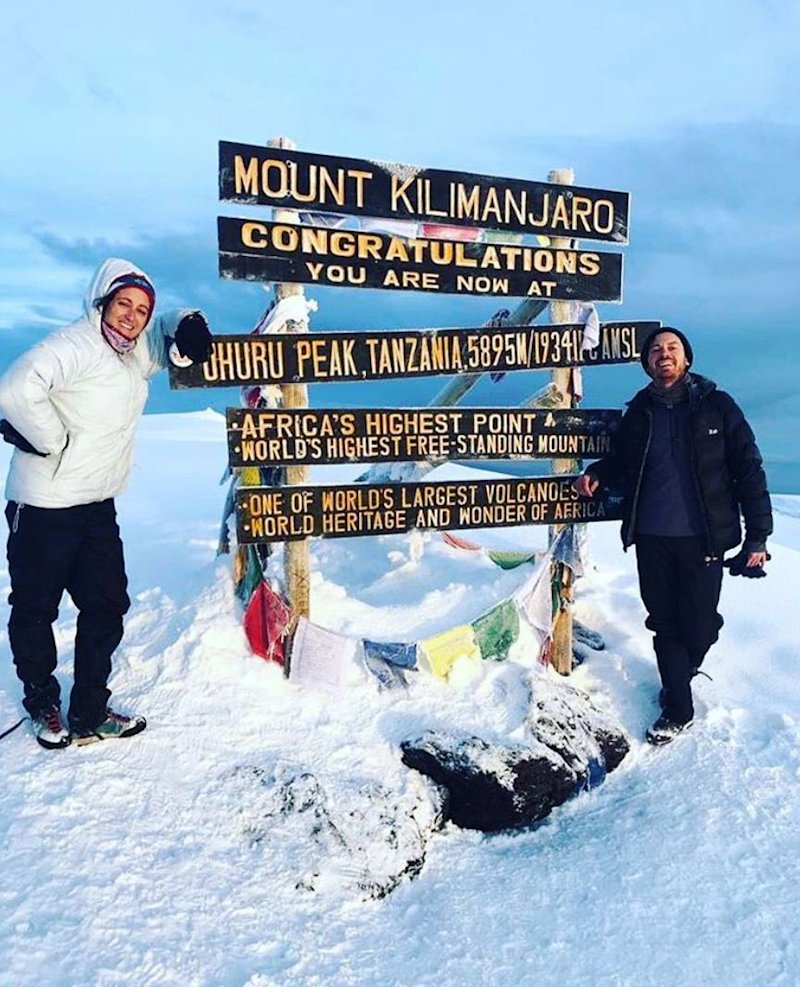 Two trekkers smiling by Uhuru Peak on a very snow-covered Kilimanjaro summit