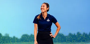 A smiling female golfer at IMG Academy standing on a course, representing positive self-talk and mental confidence in sports.