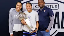 Championship winner (student-athlete) with trophy, flanked by two proud adults (coaches/parents), celebrating at the Chipotle Nationals basketball tournament.