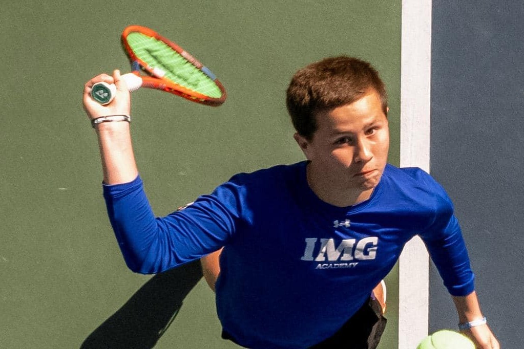 Male tennis player preparing to serve, captured from an overhead angle on the court.